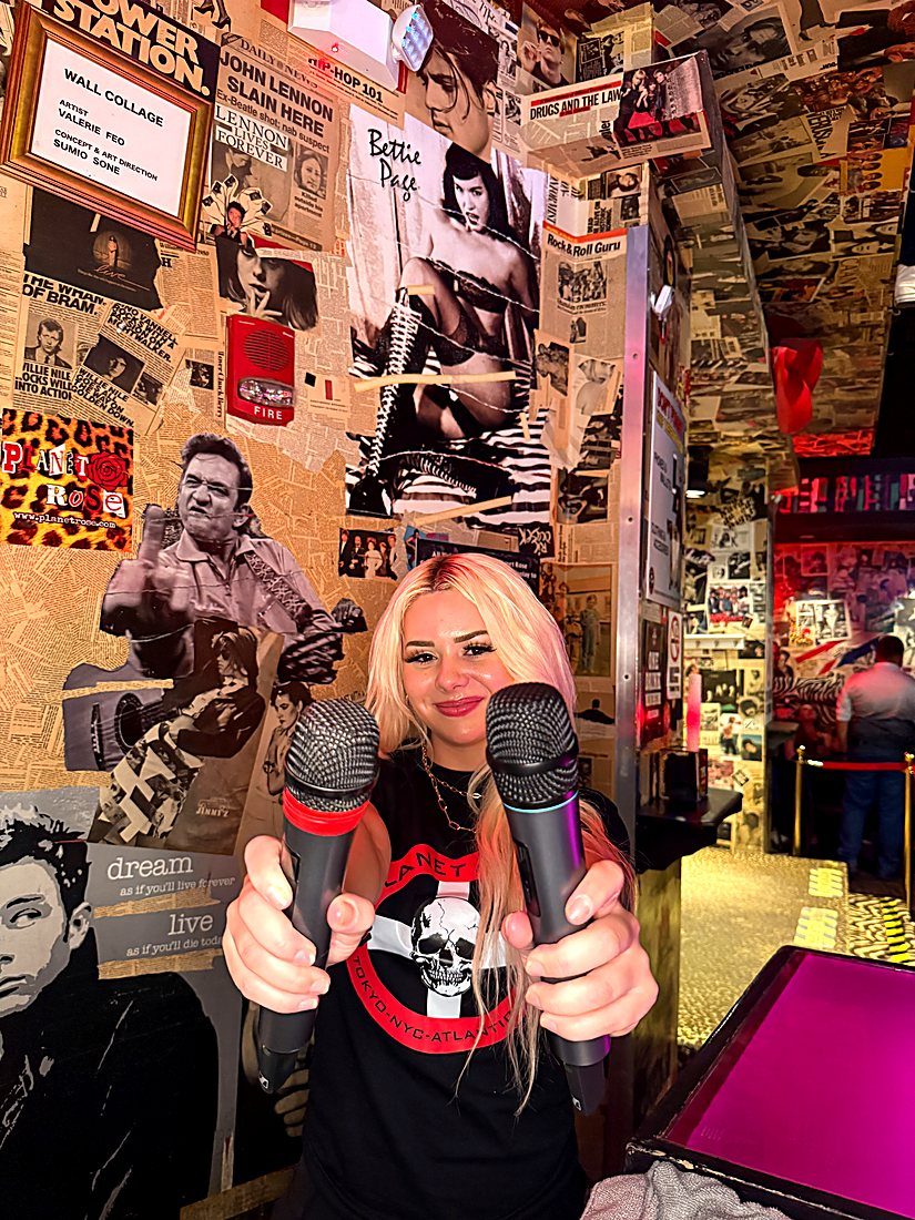 A guest in a Planet Rose tee holding out two microphones