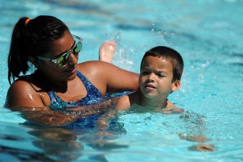 Pelatih membimbing seorang anak laki-laki berenang