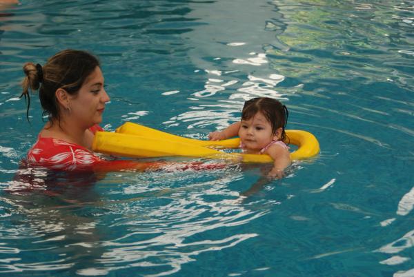Ibu mendampingi bayi mengapung dengan pelampung di kolam