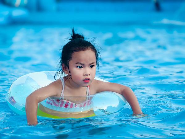 Anak perempuan bermain dengan ban pelampung di kolam