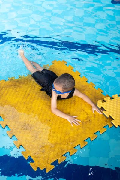 Anak berlatih meluncur di atas matras apung