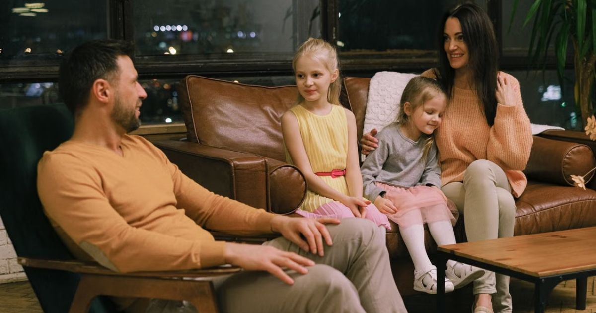 A family sitting together on a living room sofa having an engaging conversation