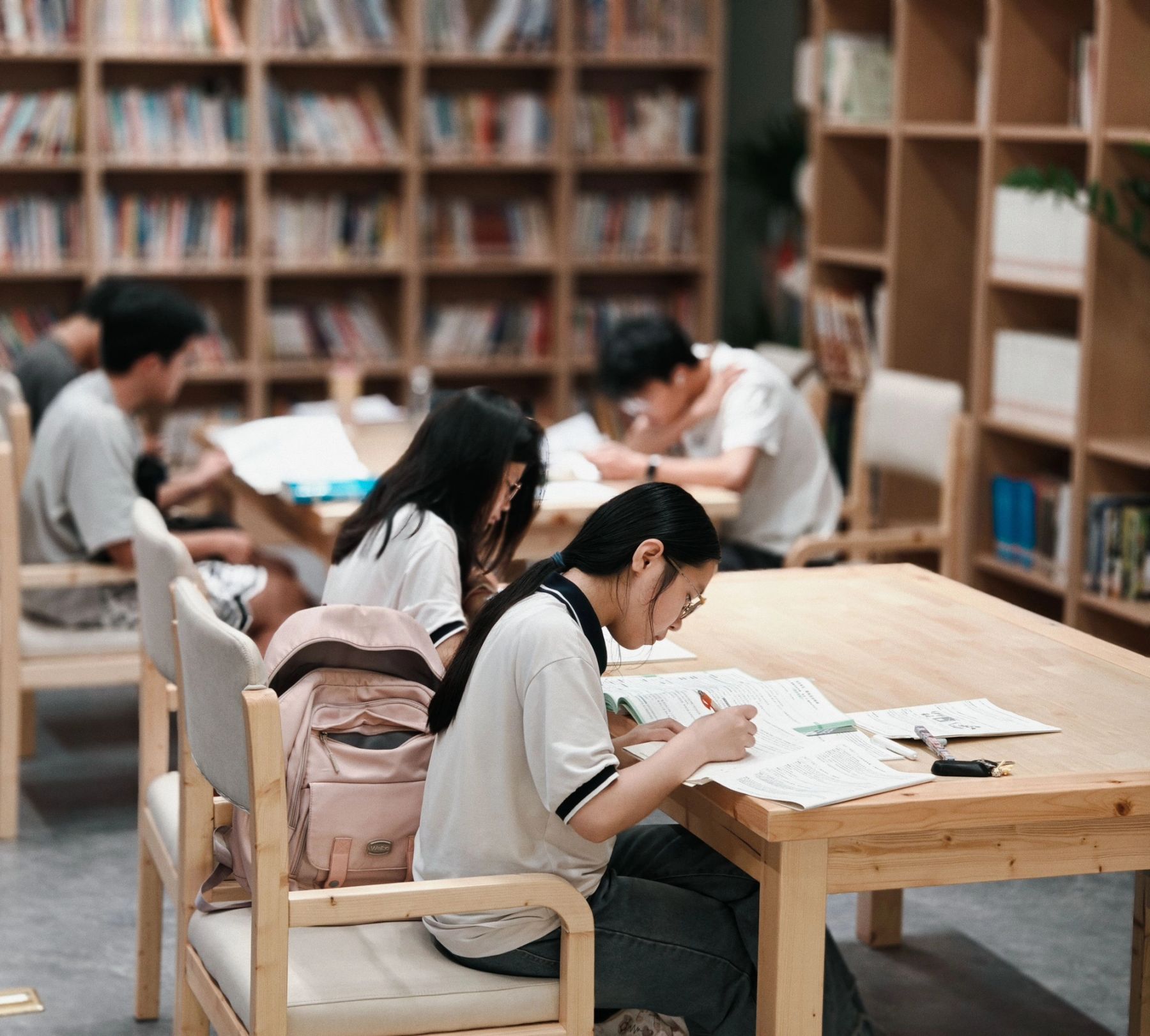 Students studying together at a table in a school library with textbooks