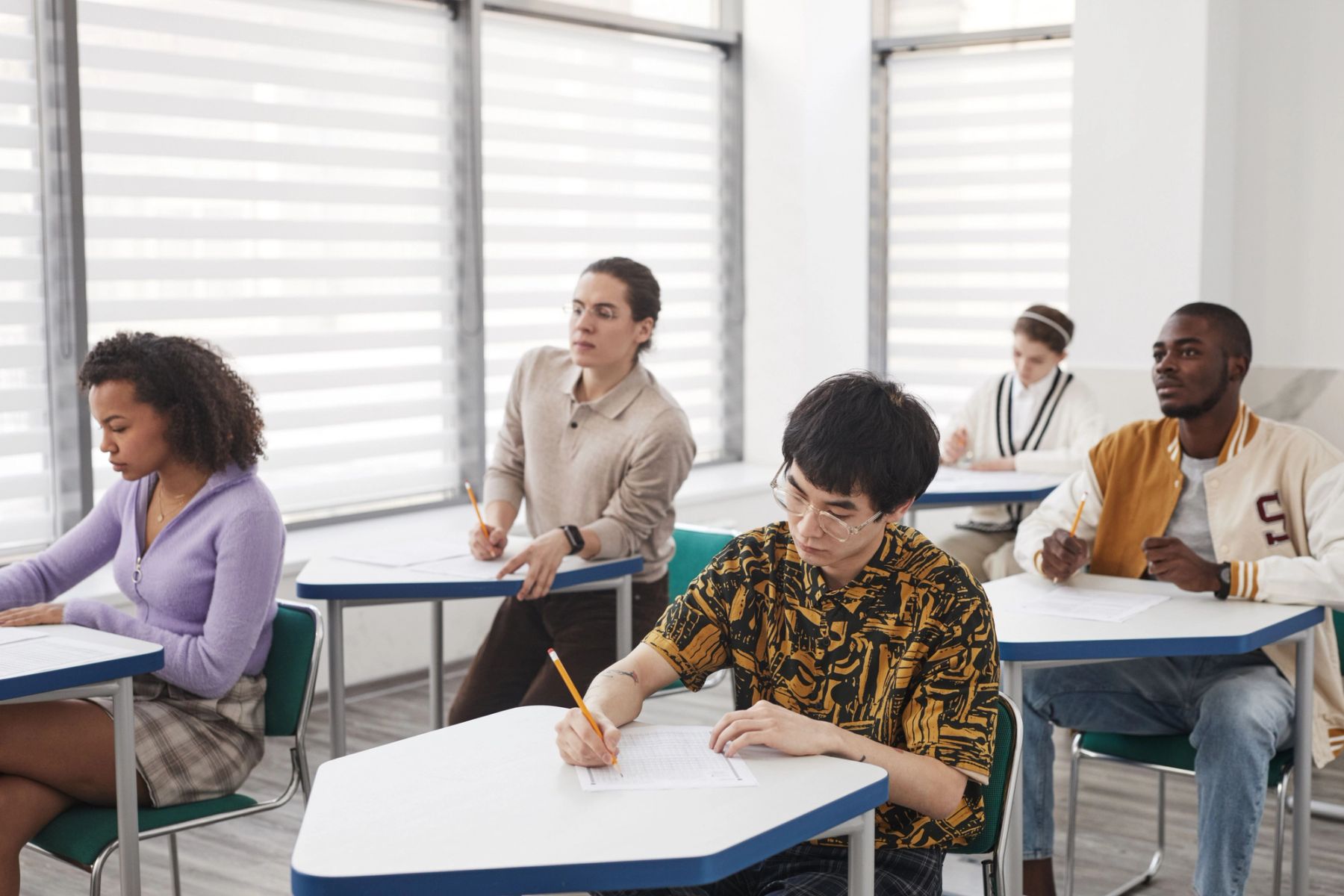 UK secondary school students taking a formal examination at individual desks in a hall
