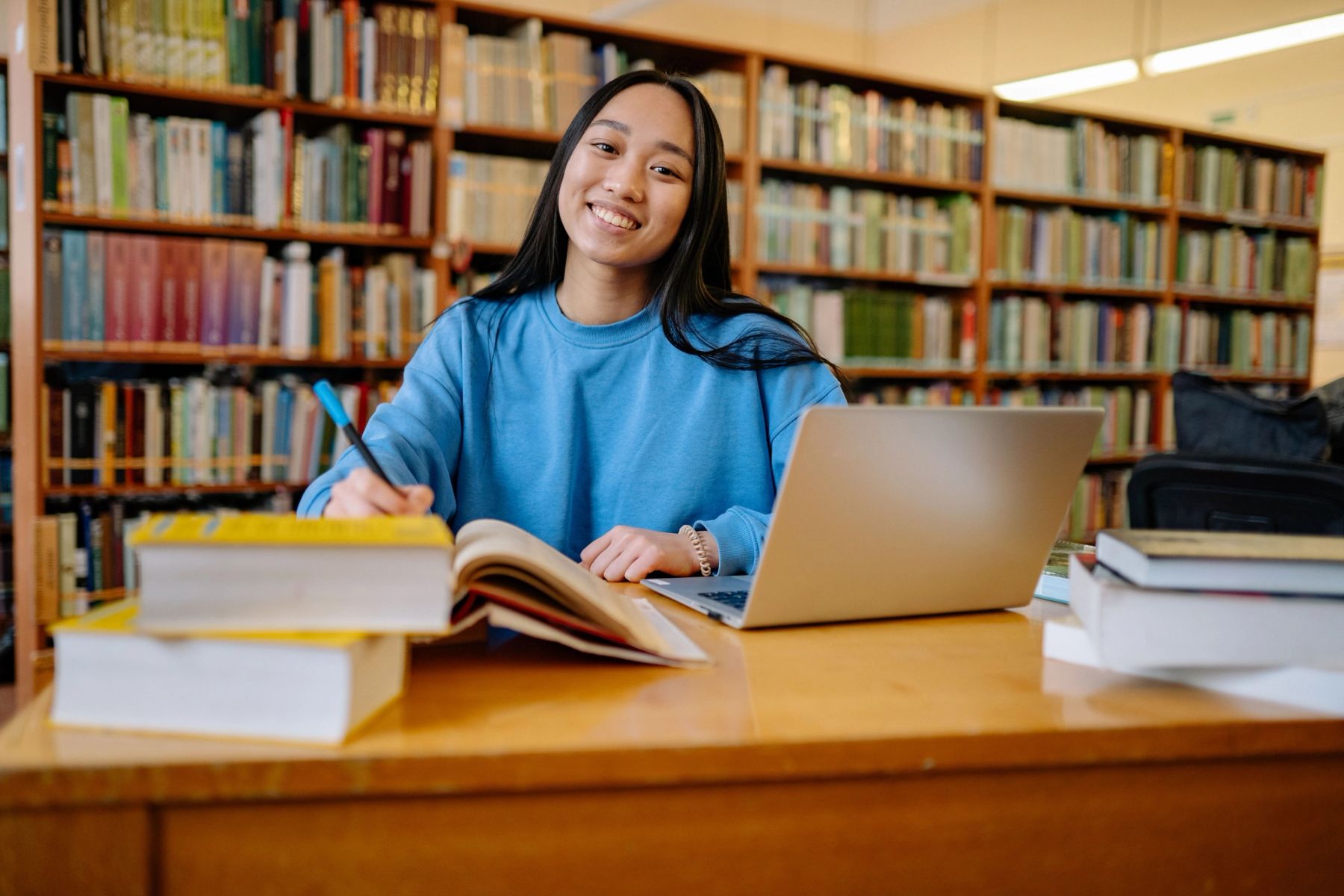 A young student reviewing exam revision materials and writing notes at a tidy desk