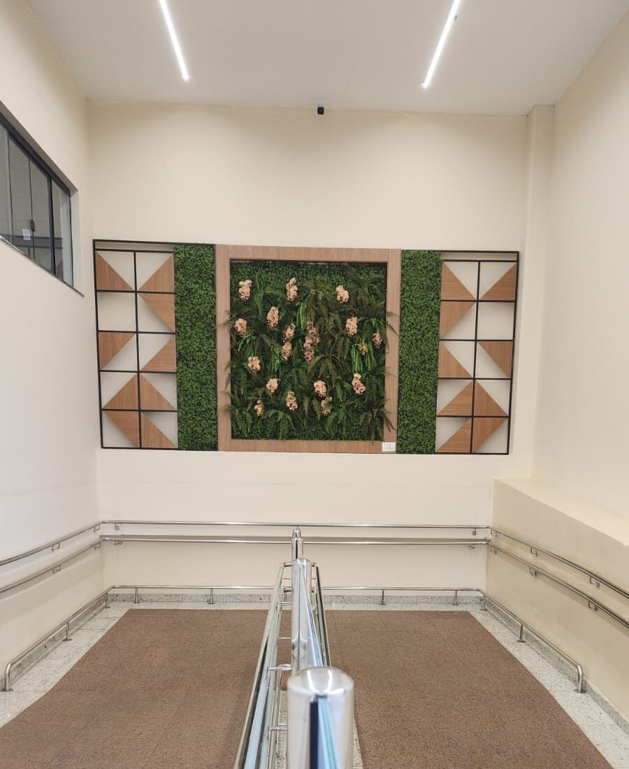 Quadro verde com orquídeas entre painéis geométricos, no alto do corredor de entrada