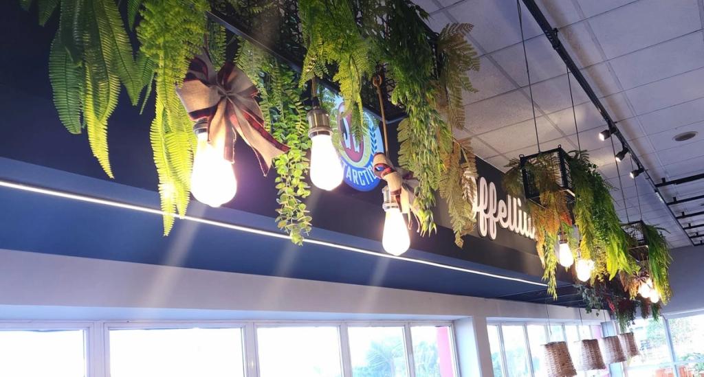 Detalhe das folhagens pendentes e das lâmpadas sobre o letreiro