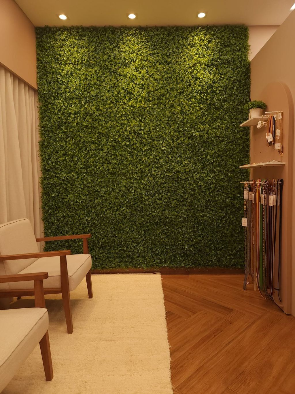 Provador da Loja Saia de Seda com parede inteira de jardim vertical, poltrona de madeira e tapete claro