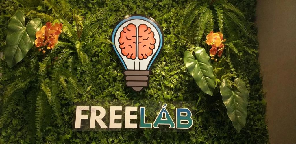 Detalhe do logotipo da Free Lab cercado por folhagens e flores
