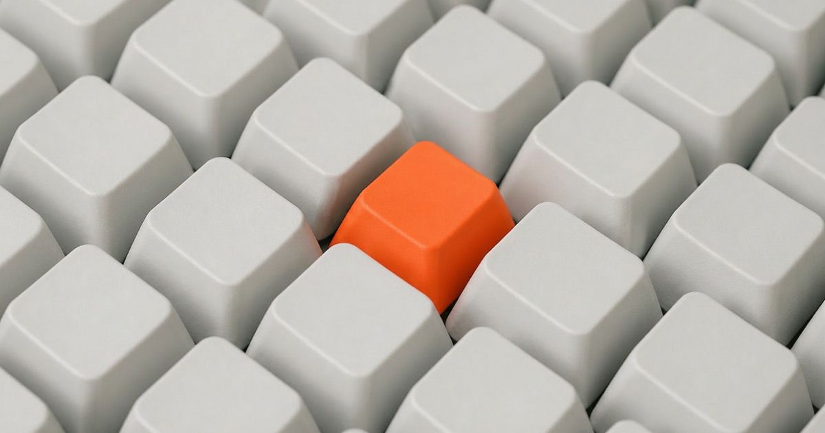 A single orange keycap standing out in a grid of identical white keycaps, representing AI governance bringing order to scattered AI experiments