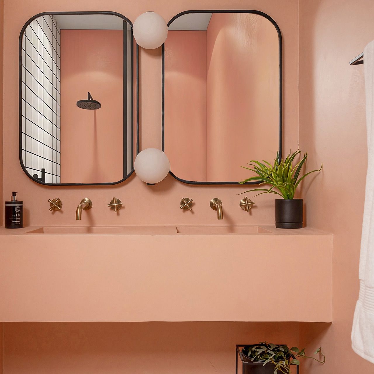 Coral microcement bathroom with a seamless poured basin and brass fittings