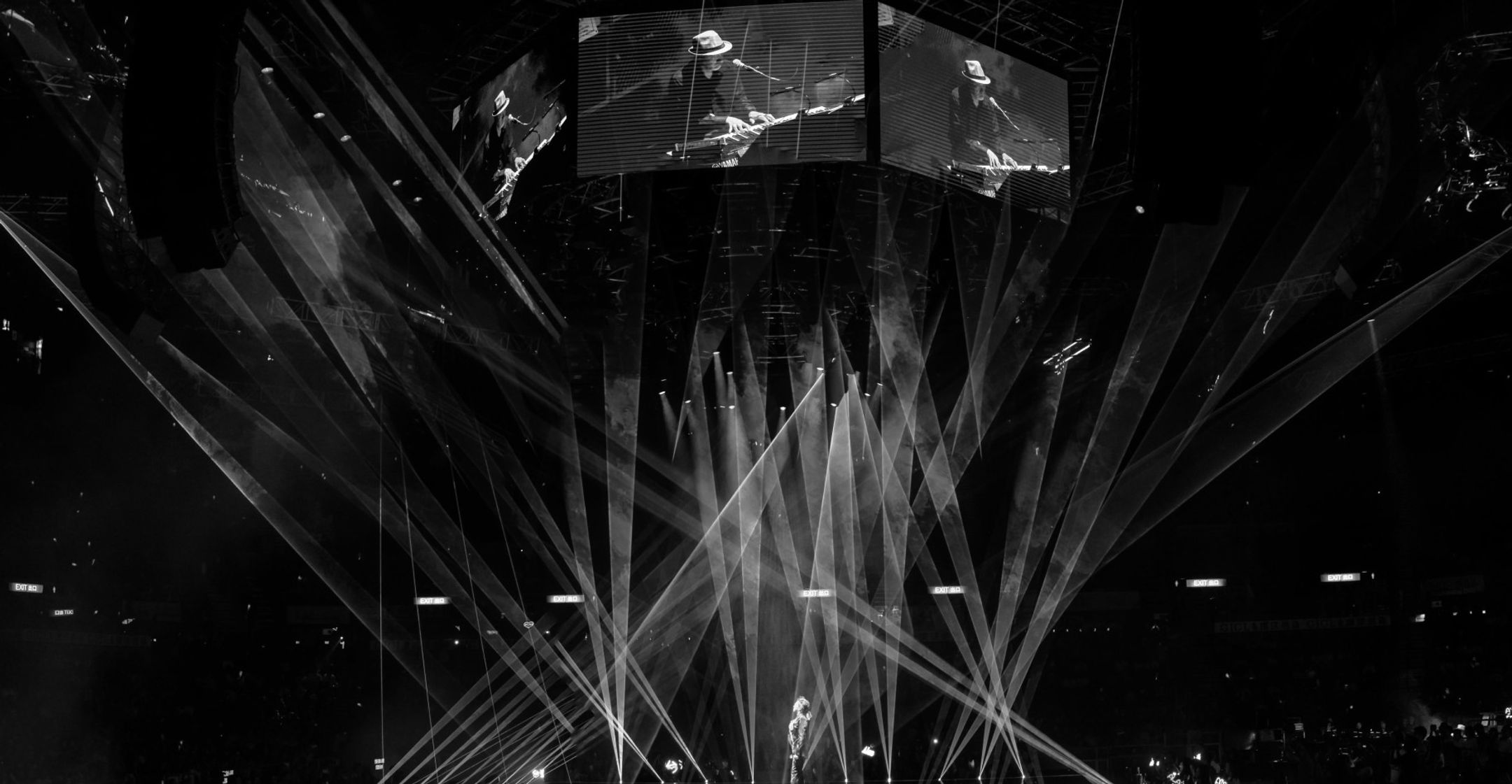 A live stage lit by dramatic beams of light over a crowd