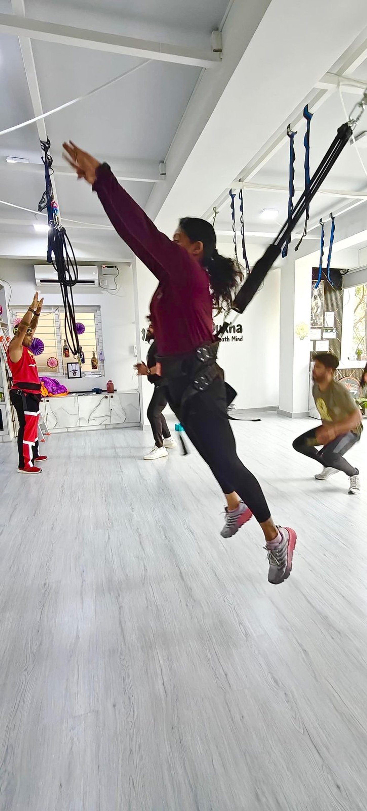 Bungee Fit squat in harness with Sukha studio branding behind