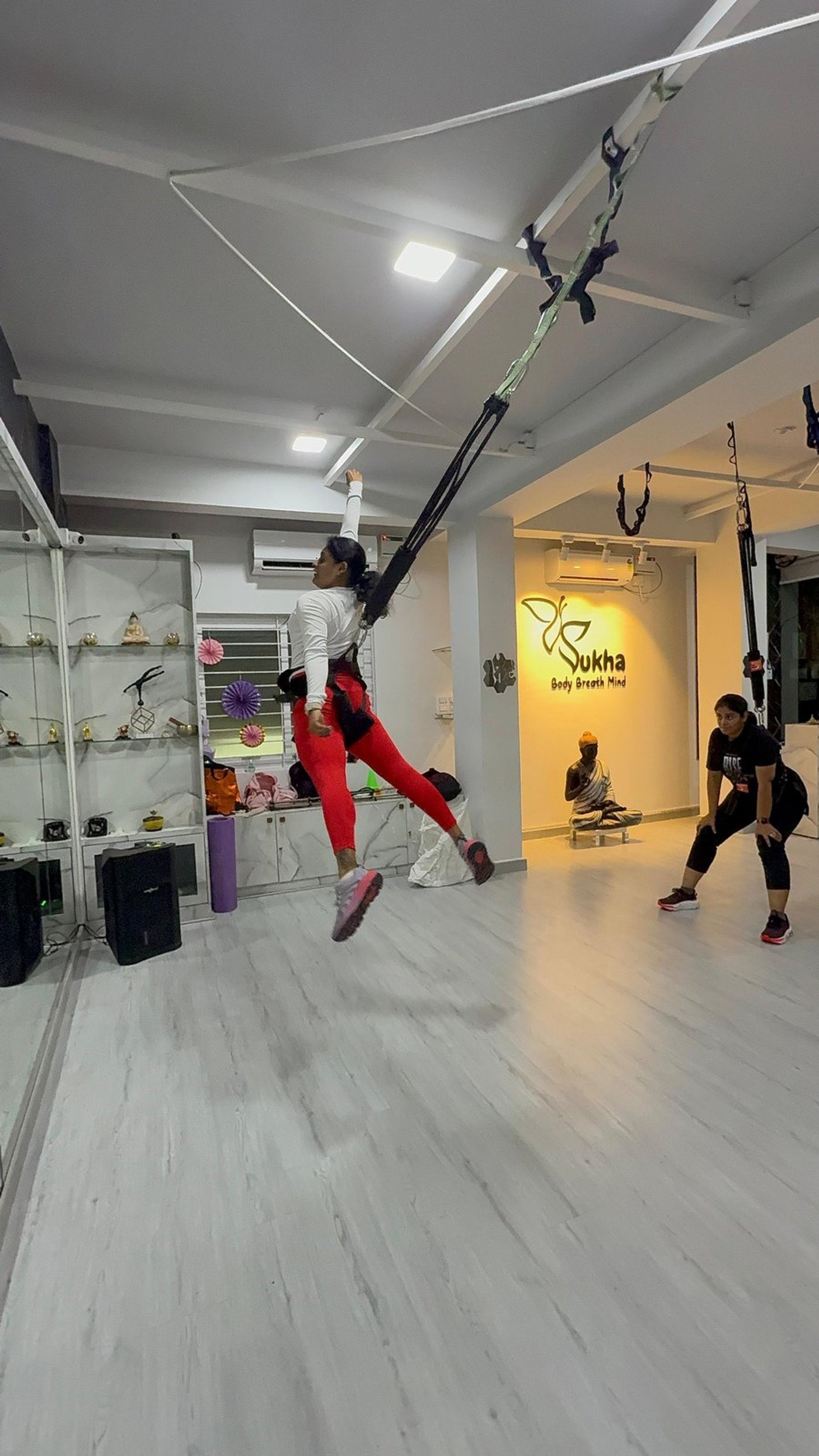 Three athletes in a Bungee Fit class leaning forward on cords