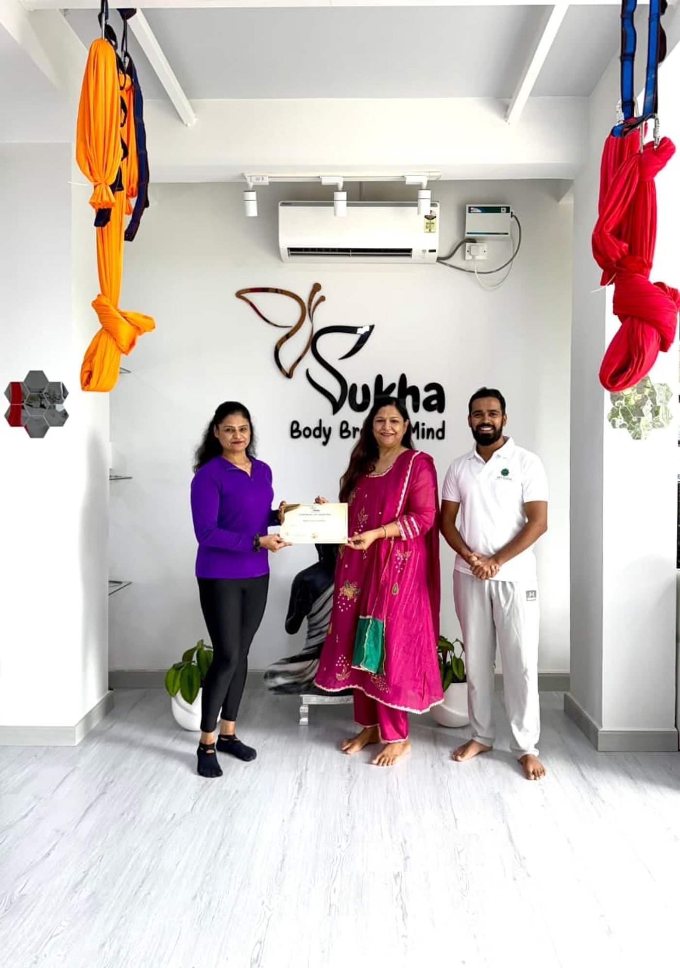 Trainers and a graduate posing with a course certificate