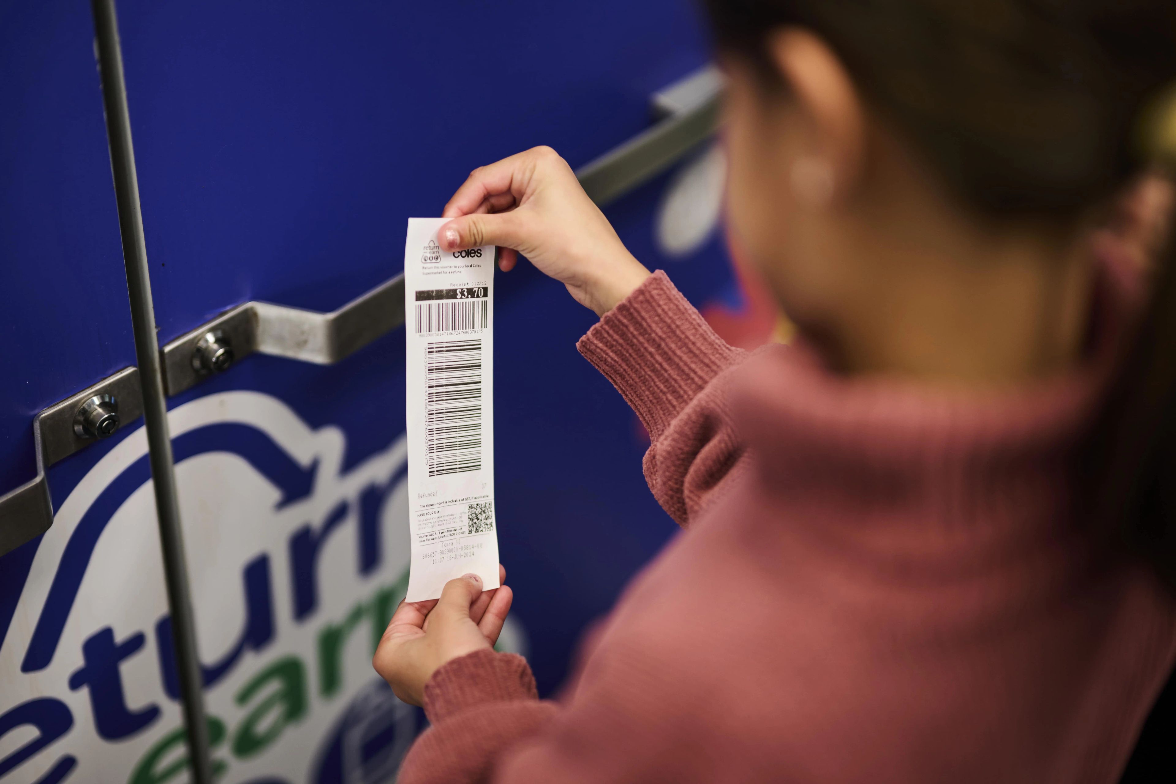 Photo of a person holding a receipt for return and earn