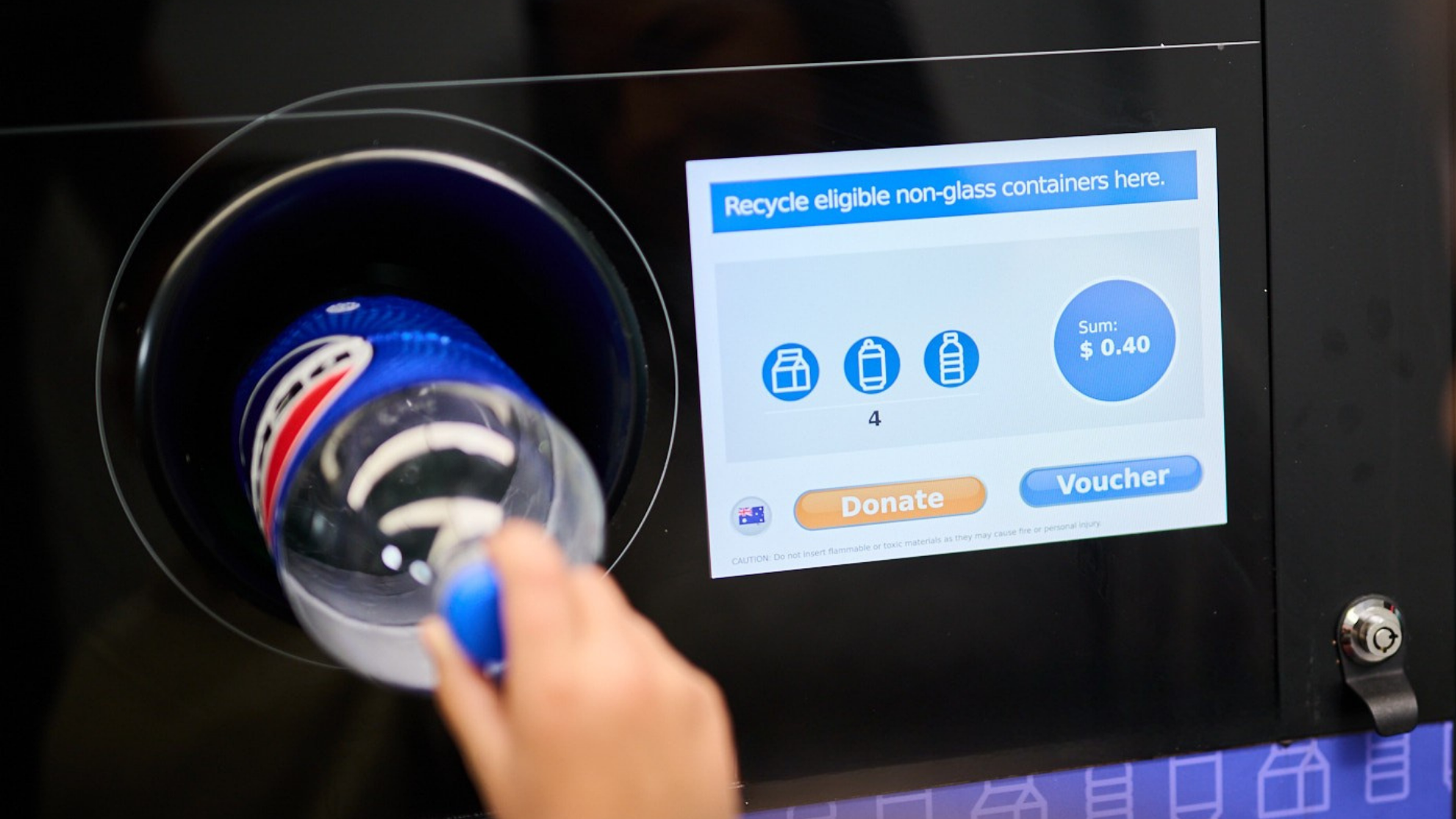 A hand placing a Pepsi bottle in a Return and Earn 
