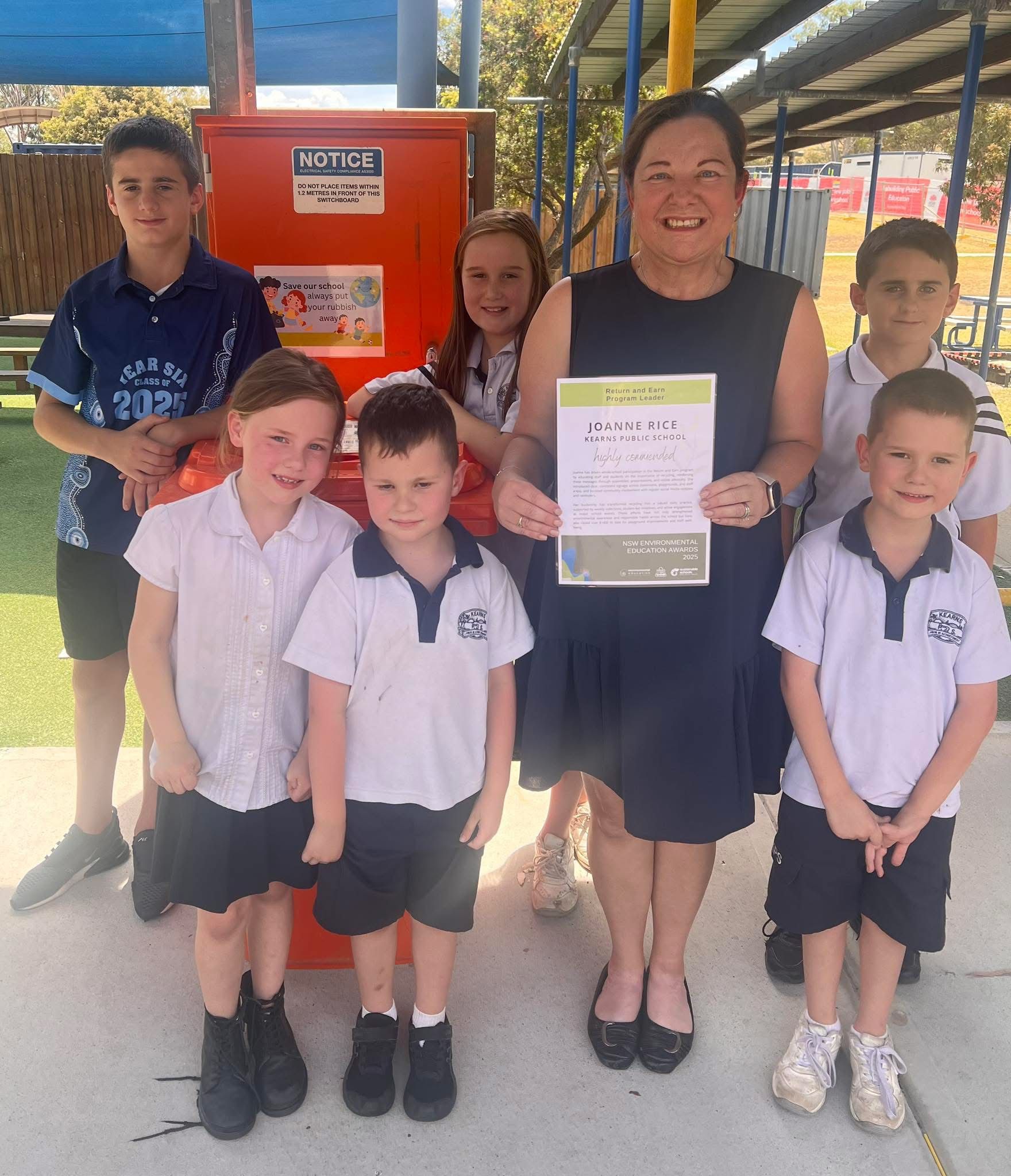 students and teacher standing with certificate