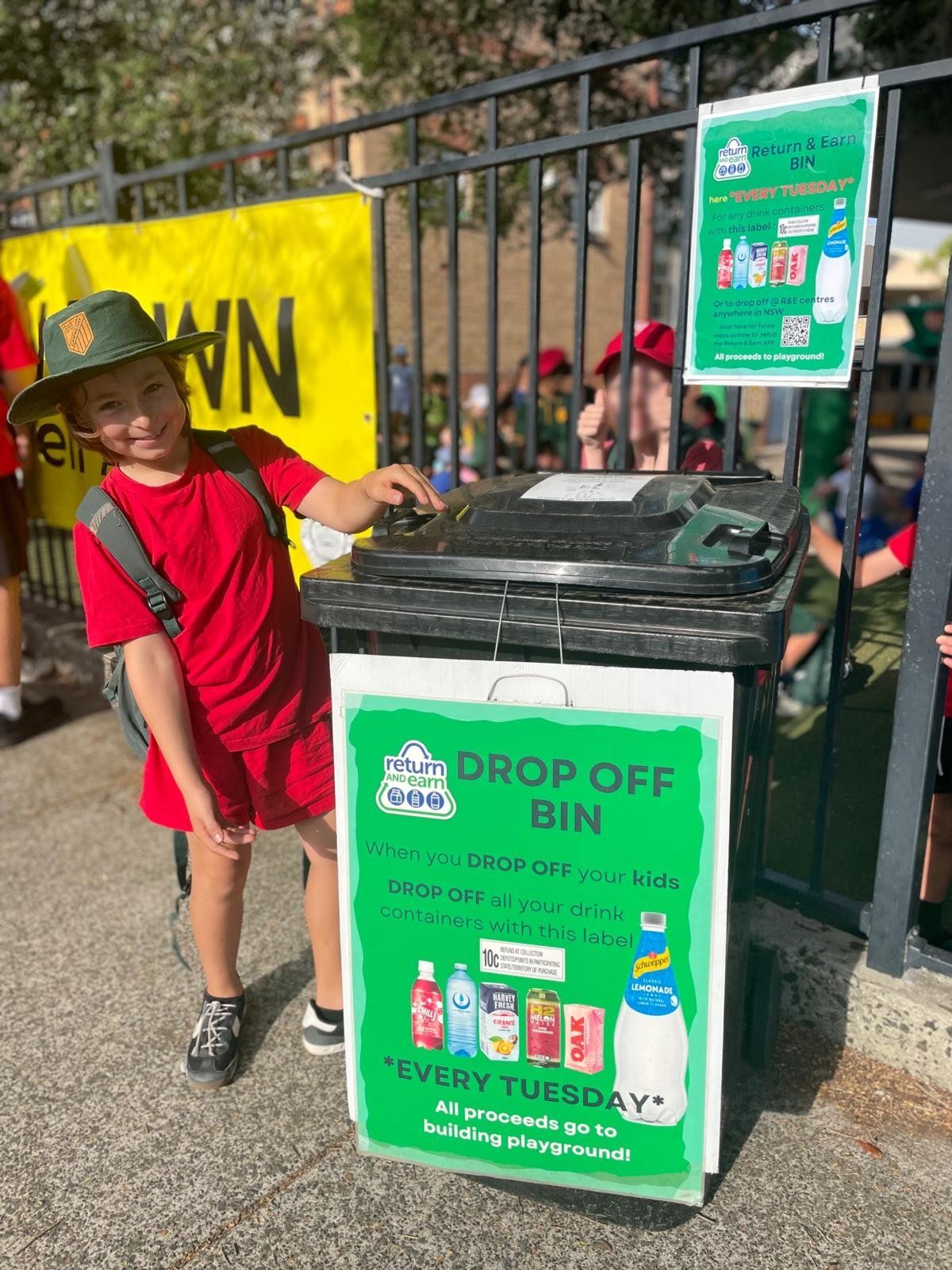 student standing beside recycling bin 