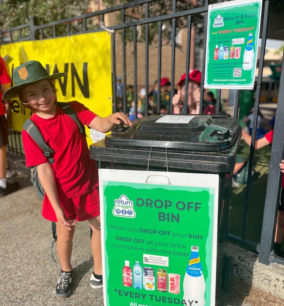student standing beside recycling bin