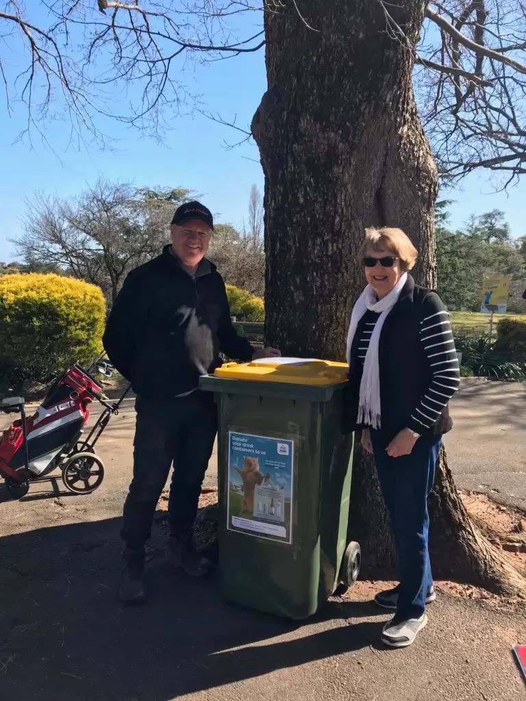 A man and women standing next to a yellow australian bin