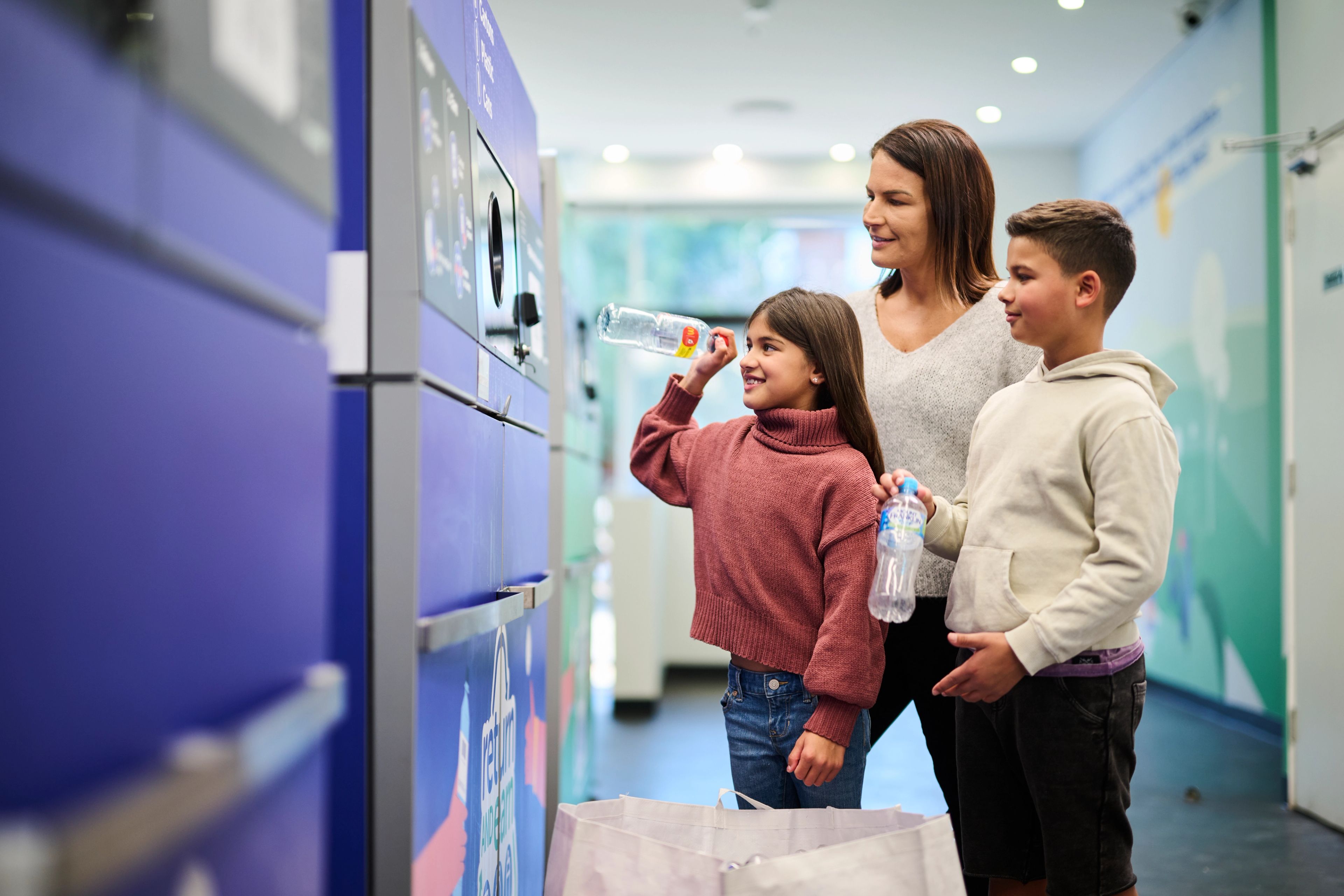 A family returning their bottles and cans at a Return and Earn centre.