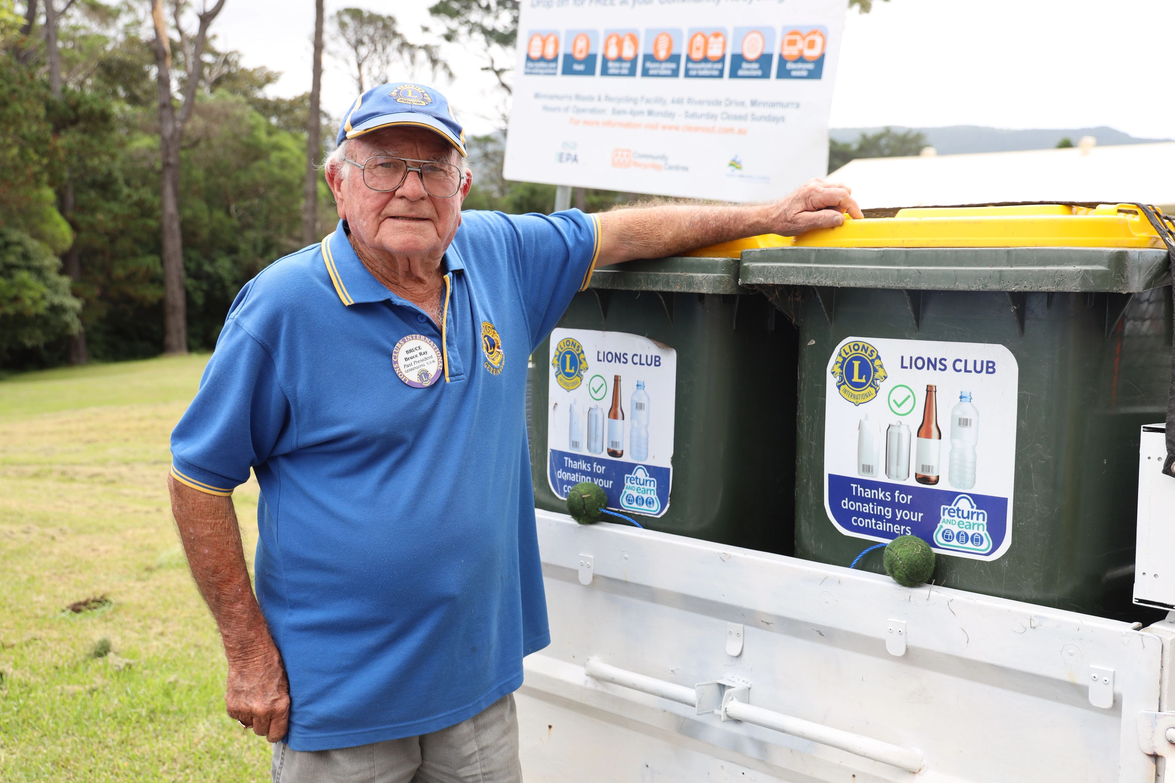 man standing beside recycling bins
