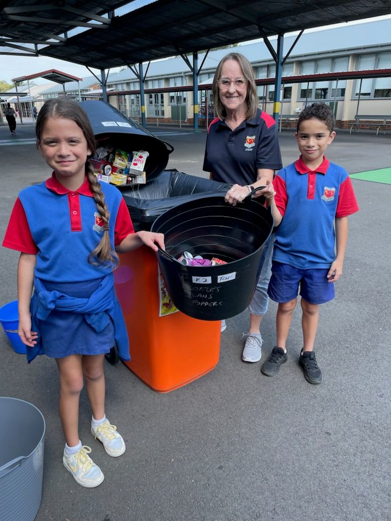 students and teachers standing beside a bin with the containers