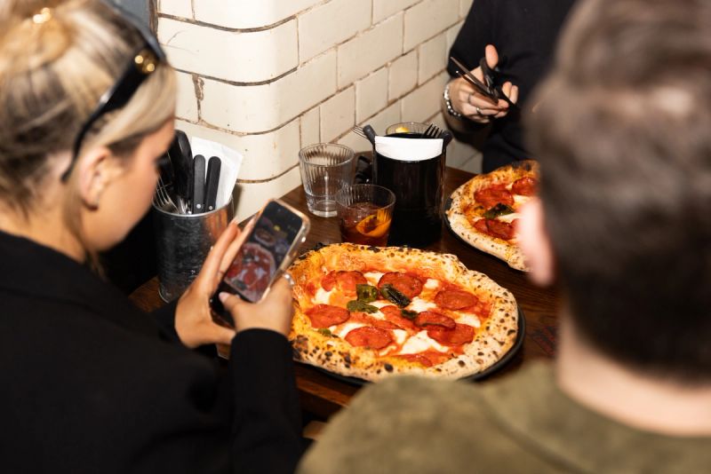 Friends about to photograph a pepperoni pizza