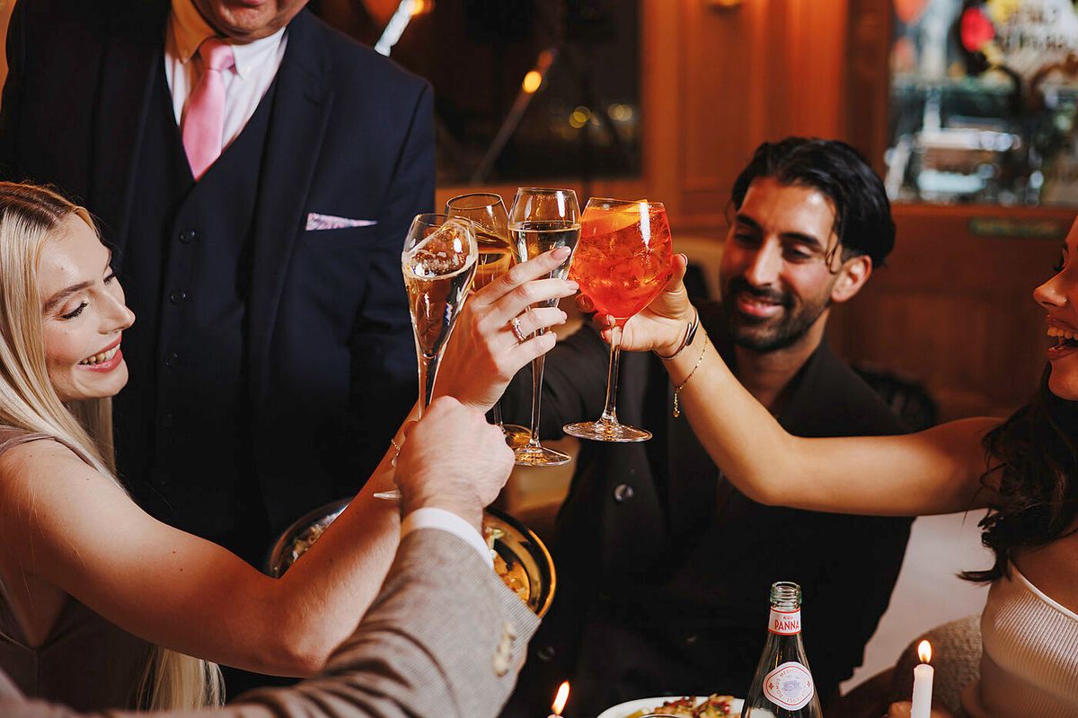 Friends raising spritz and sparkling wine glasses in celebration