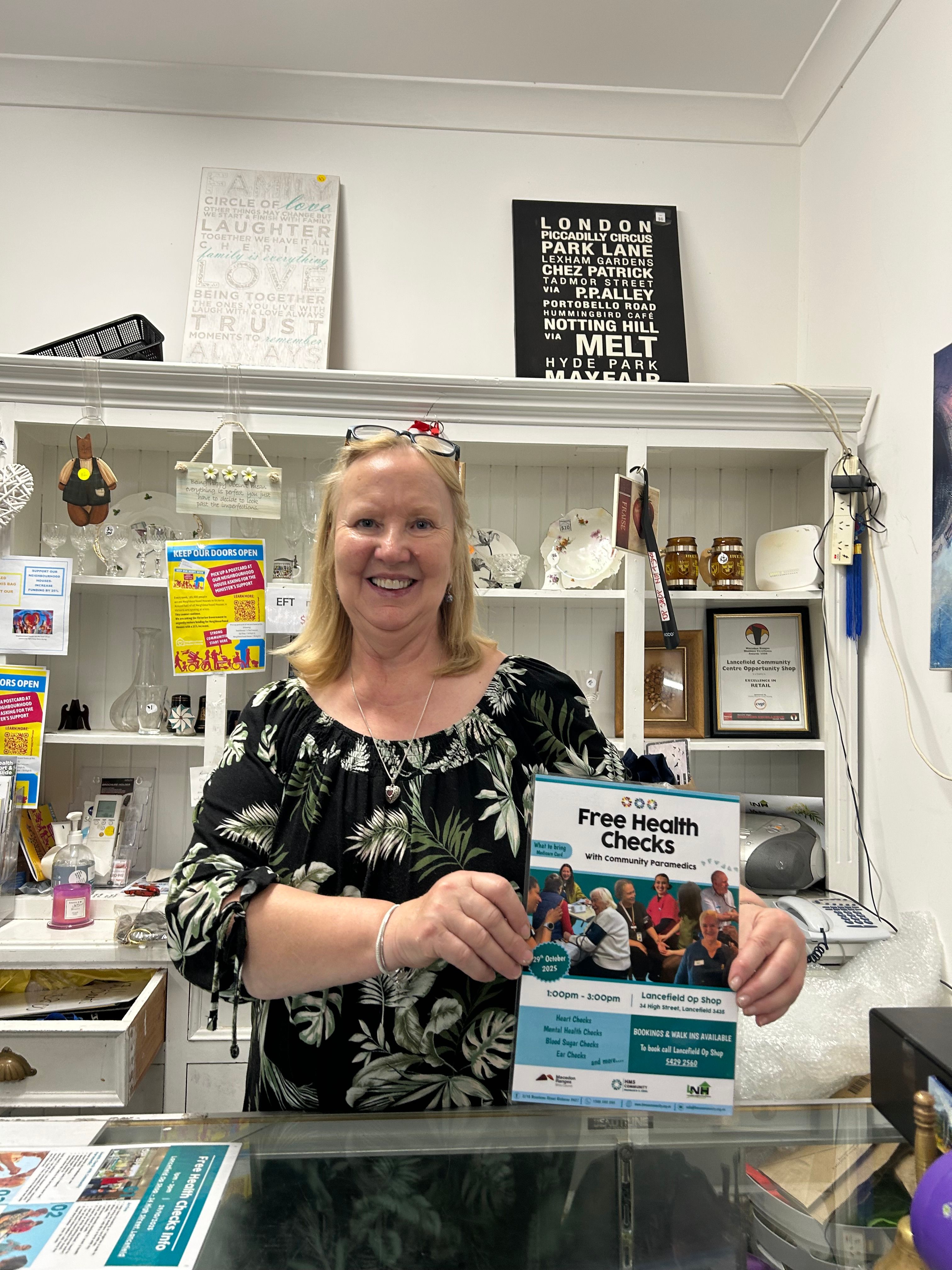 Person holding up a sign in an op shop about our health checks 