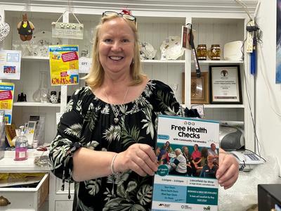 Person holding up a sign in an op shop about our health checks