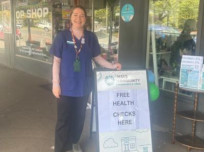Community Paramedic standing in front of a free health check sign