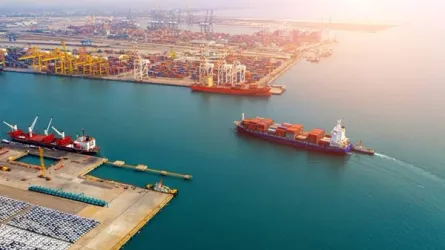 A modern, clean-energy vessel navigating near a port with wind turbines.