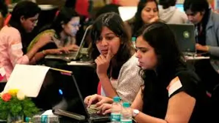 Female university students collaborating on laptops during the GirlCode AI hackathon.