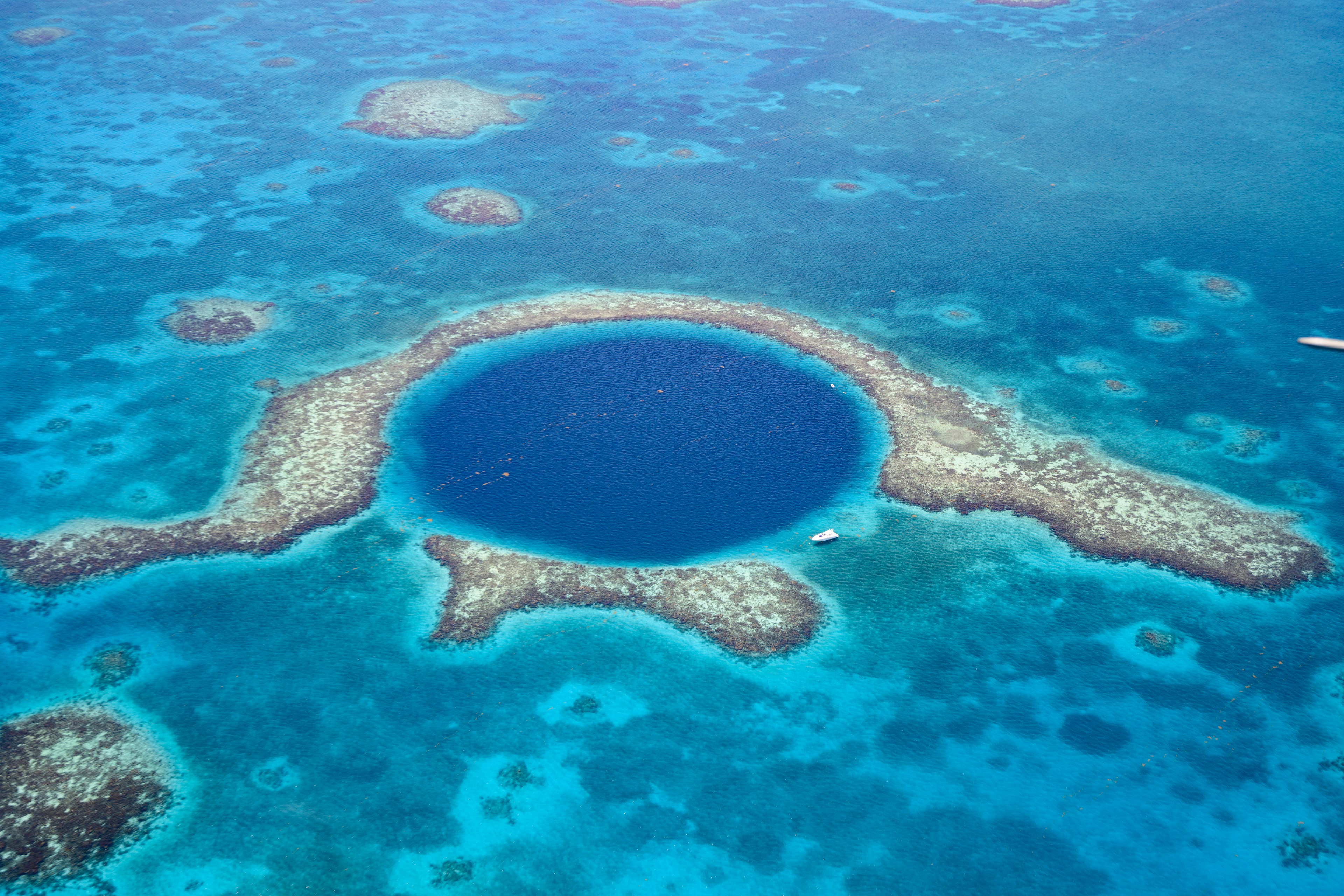 Aerial view of Great Blue Hole, a marine sinkhole and geological wonder in the Belize Barrier Reef Reserve, which is no longer on the UNESCO Danger List./Getty Images