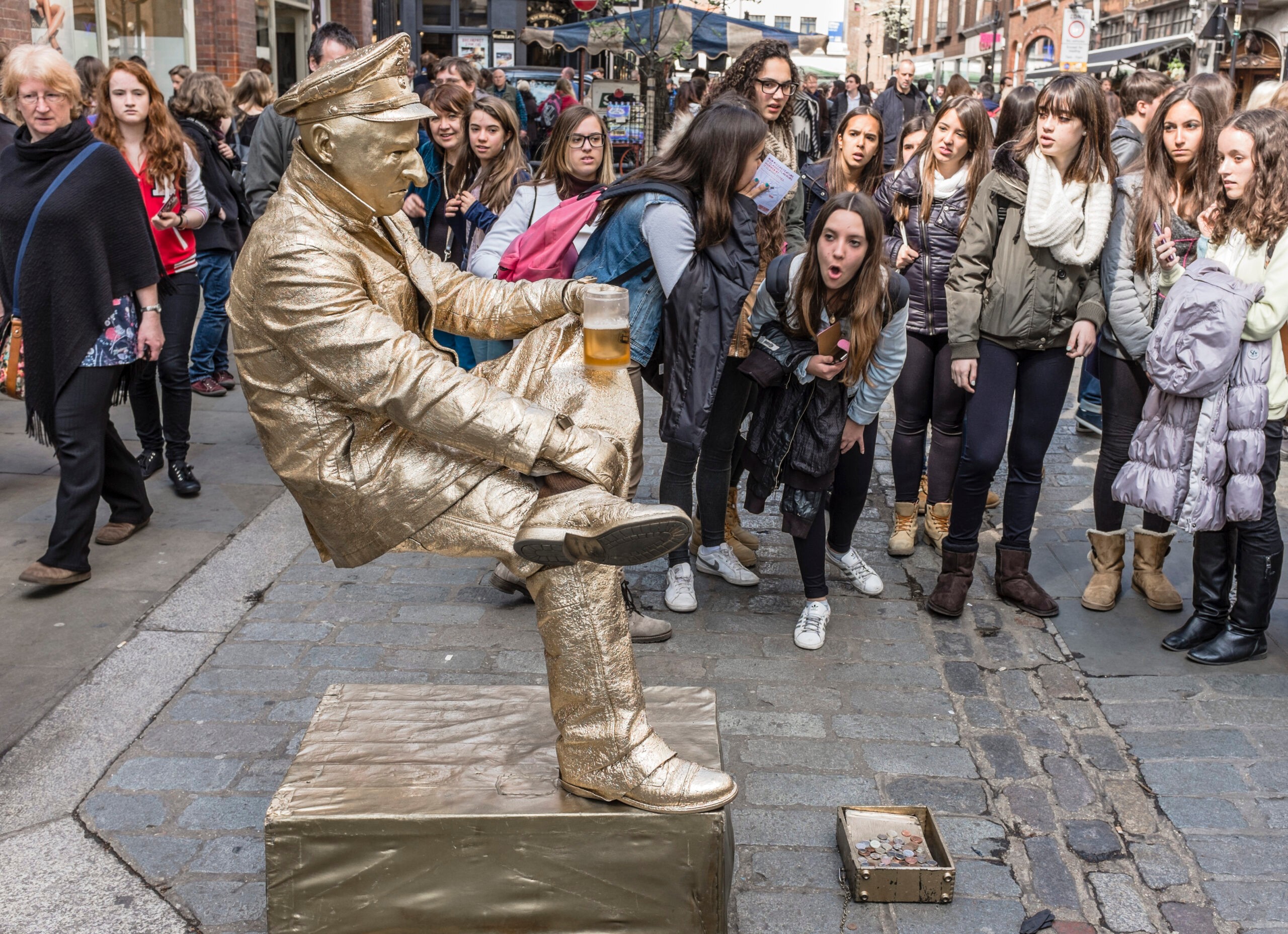 London, England - April 11th, 2014 : A street entertainer/busker entertaining a crowd of onlookers by appearing to balance unsupported whilst drinking a beer at Covent Garden in Central London.