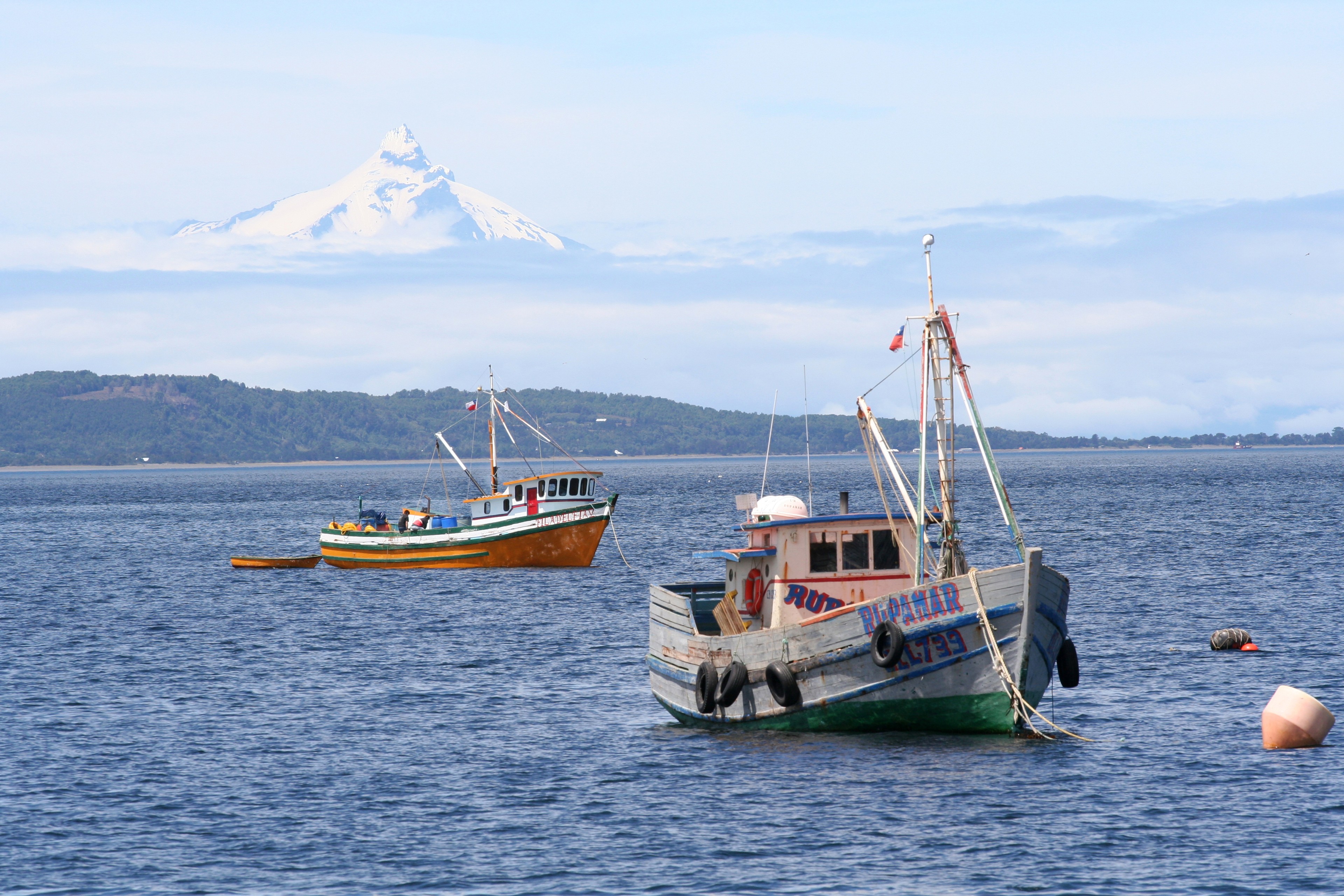 Fishing boats in the Chiloé archipelago off Chile with the Corcovado Volcano on the mainland looming in the distance./Photo by Nicholas Gill