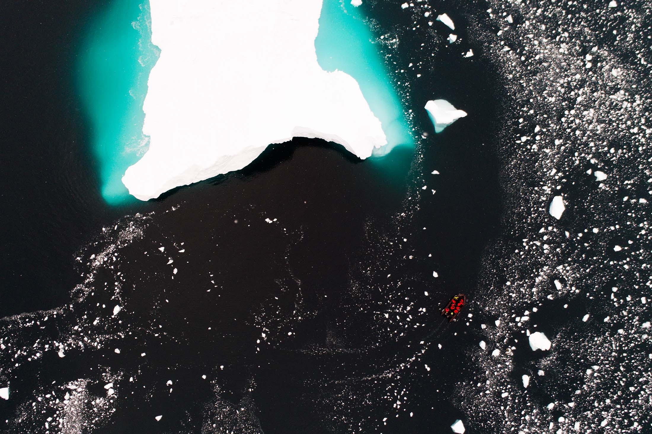An iceberg dwarfs a Zodiac at Cierva Cove, Antarctica./Denis Elterman