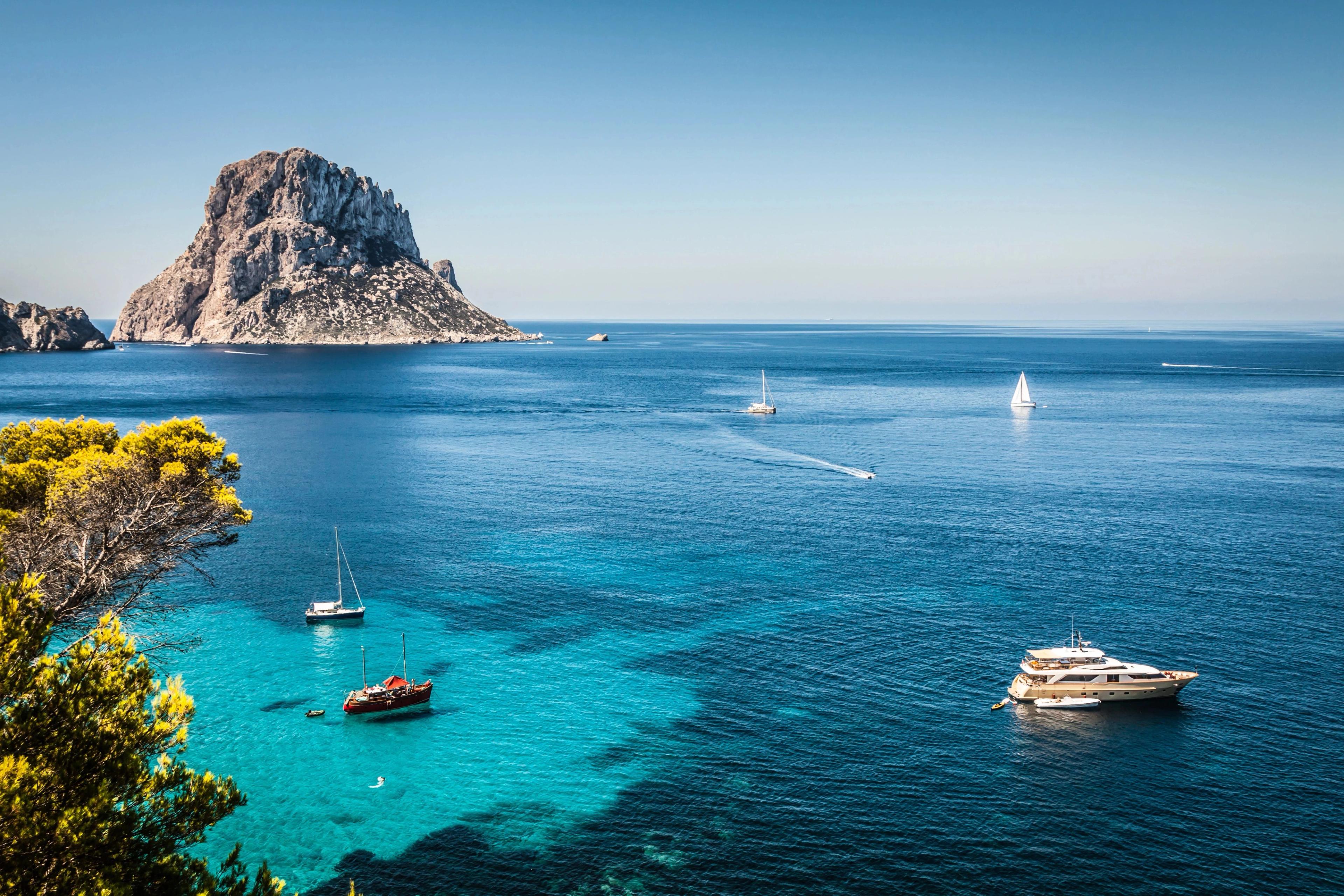 Ibiza rocky coastline highlighting distinctive Es Vedrà island landmark commanding blue Mediterranean sea waters.