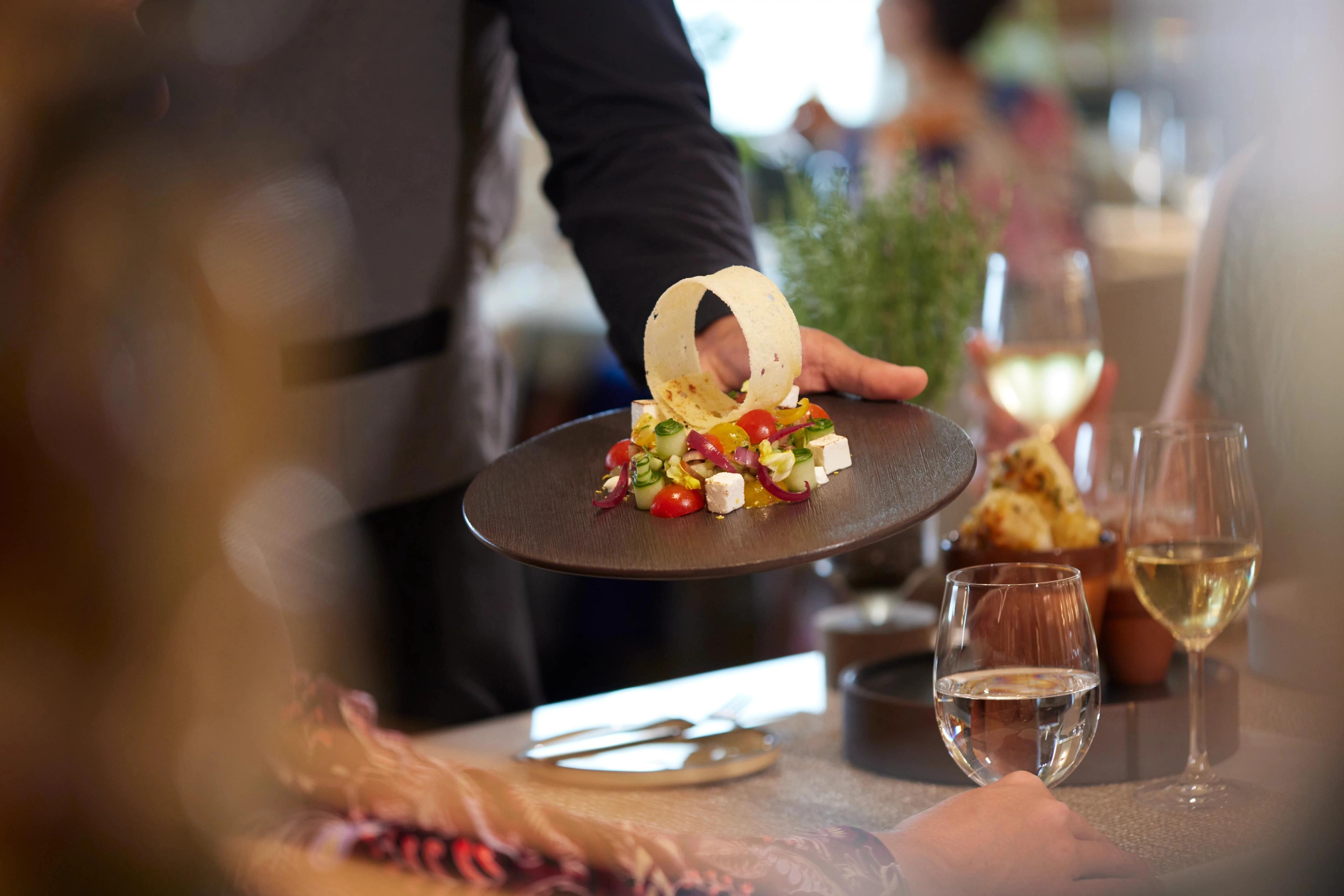 Fine dining experience featuring gourmet salads and premium wine service at the table.