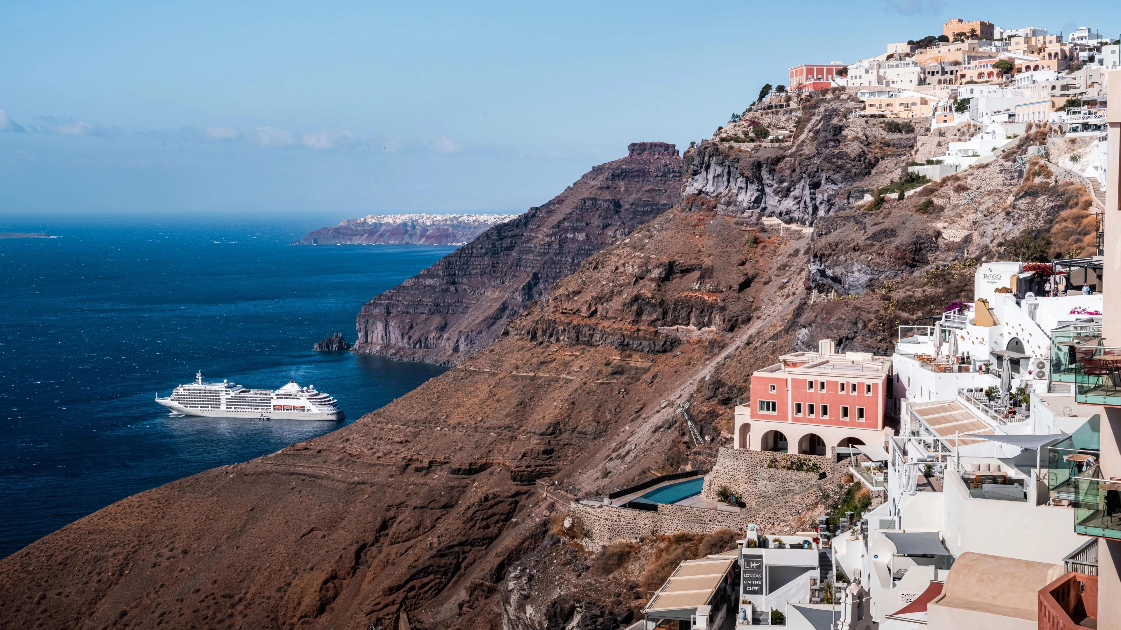 Santorini whitewashed cliffside buildings overlooking deep blue Aegean Sea waters.