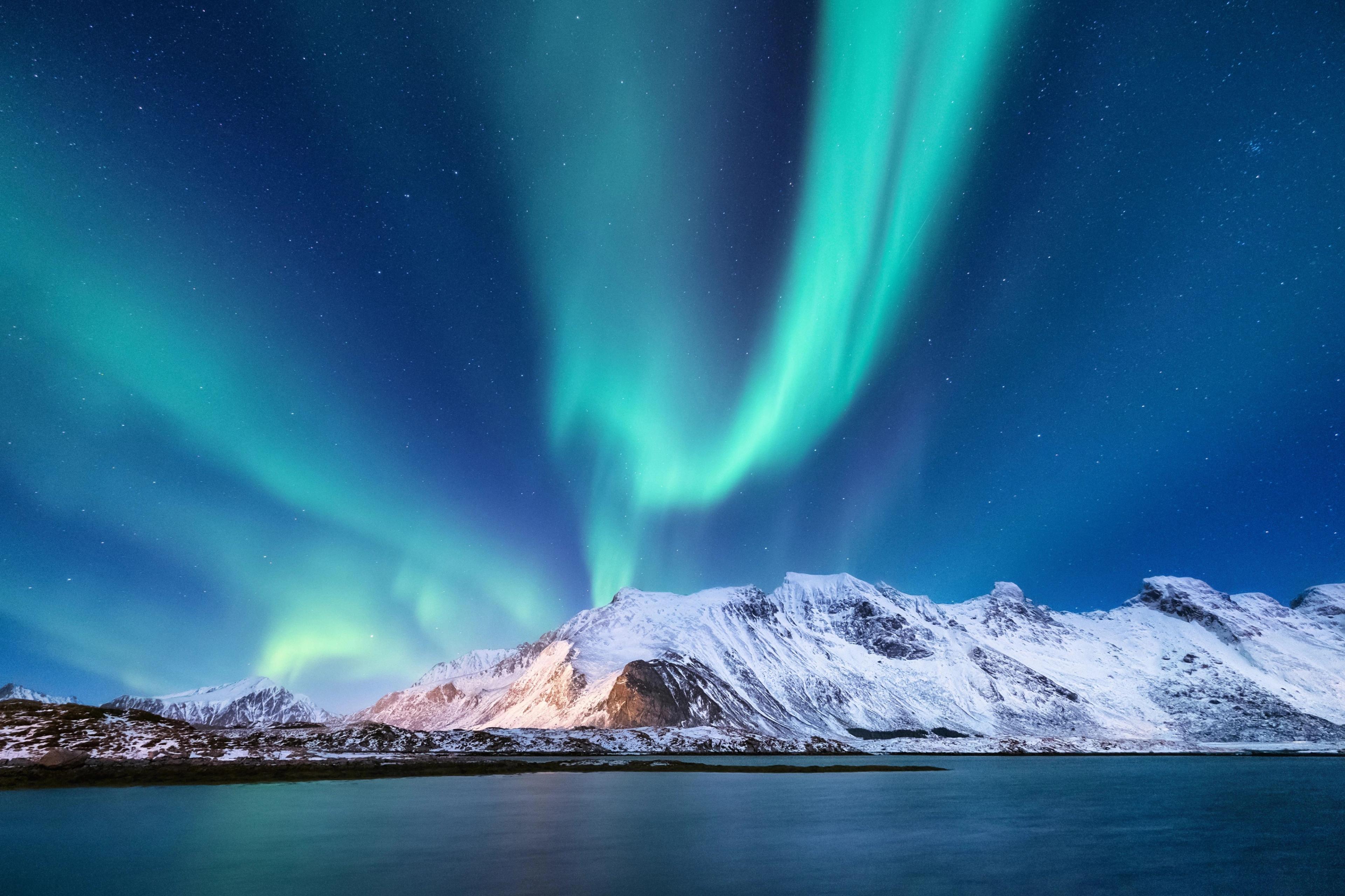 Lofoten Islands in Norway is famous for its dramatic, snow-capped mountains that rise directly from the sea, creating the perfect mirrored backdrop for the dancing lights.