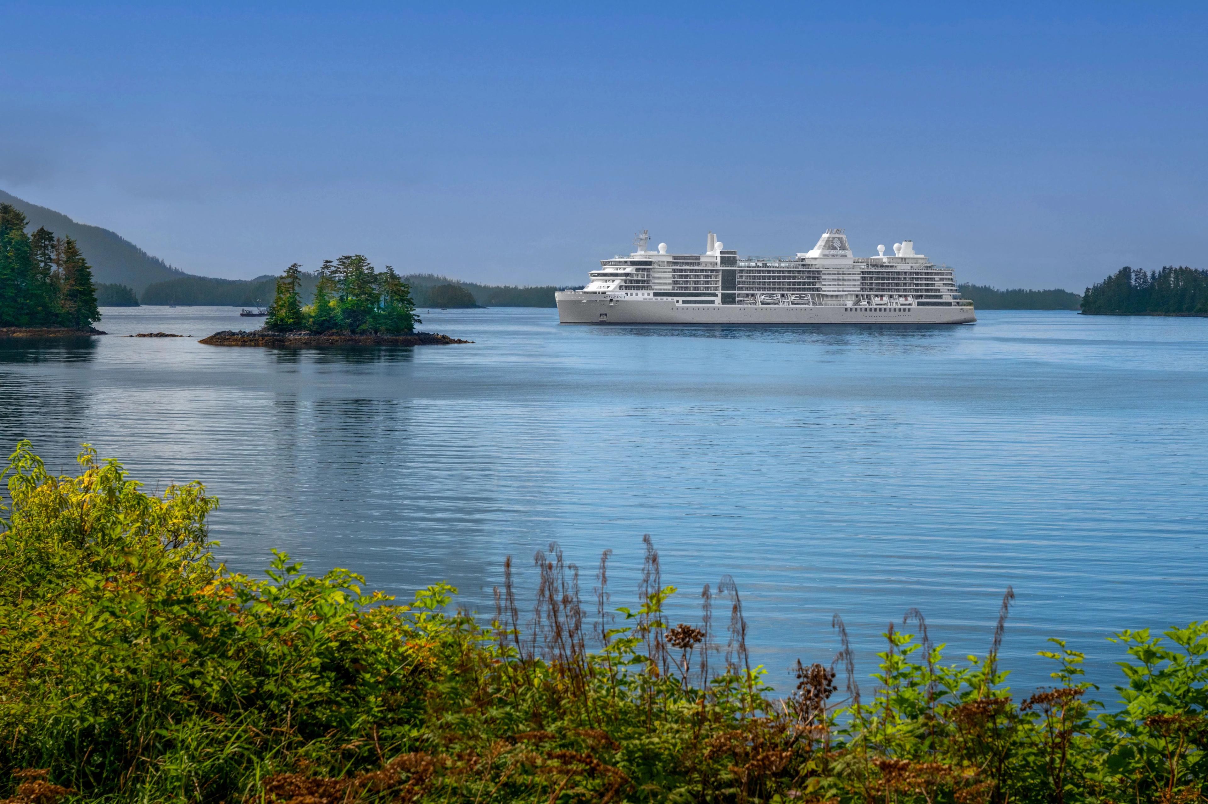 Silversea luxury cruise ship at Sitka, Alaska, framed by green pine-covered islands.