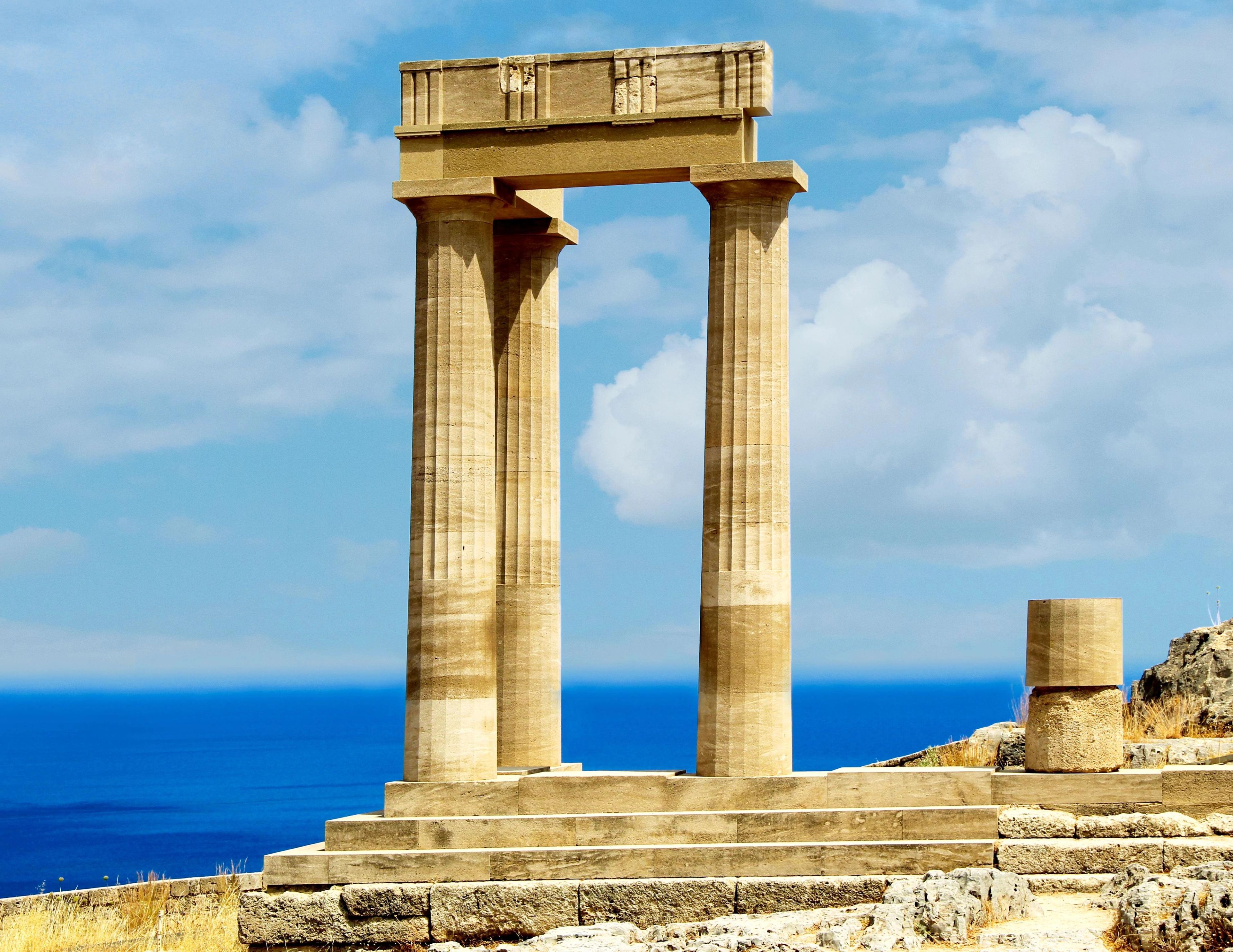 The prominent Doric columns frame a breathtaking view of the surrounding Aegean Sea.