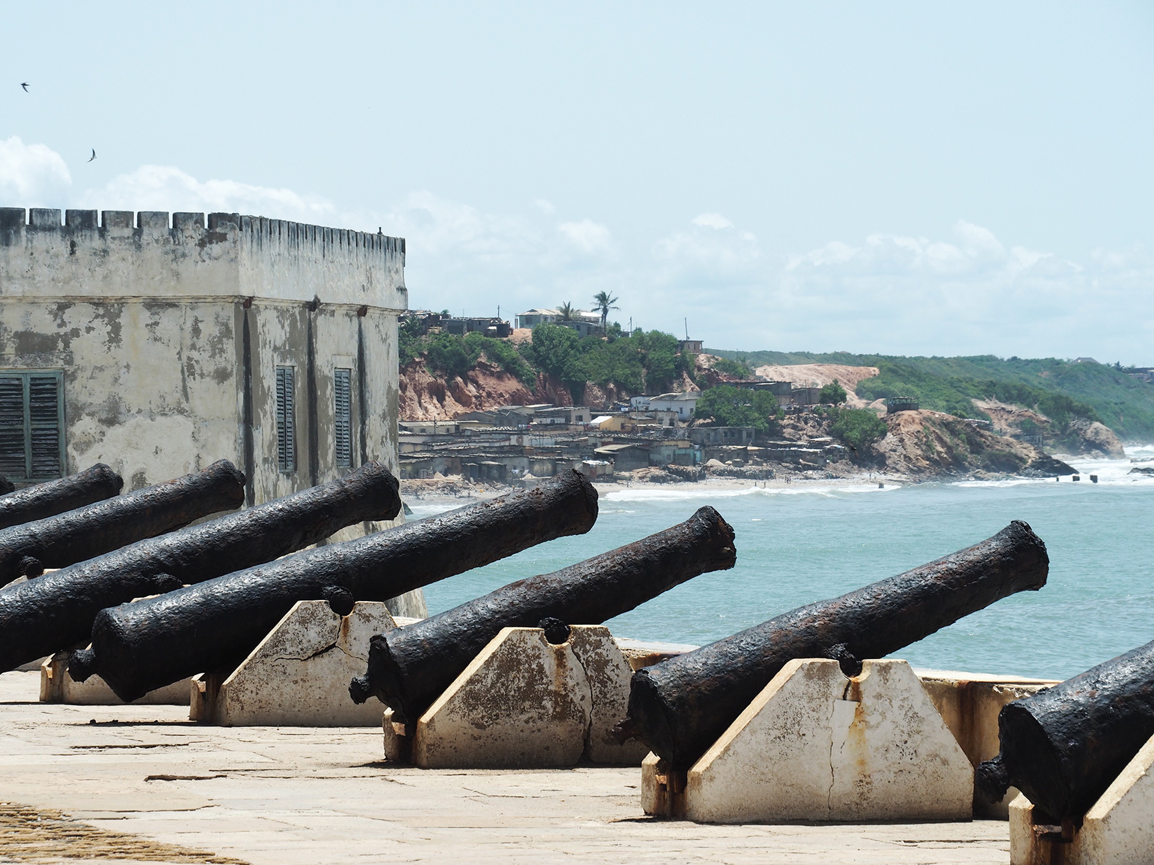 The black cannons lining the edge of Cape Coast Castle point to sea/ Alexandra Yingst