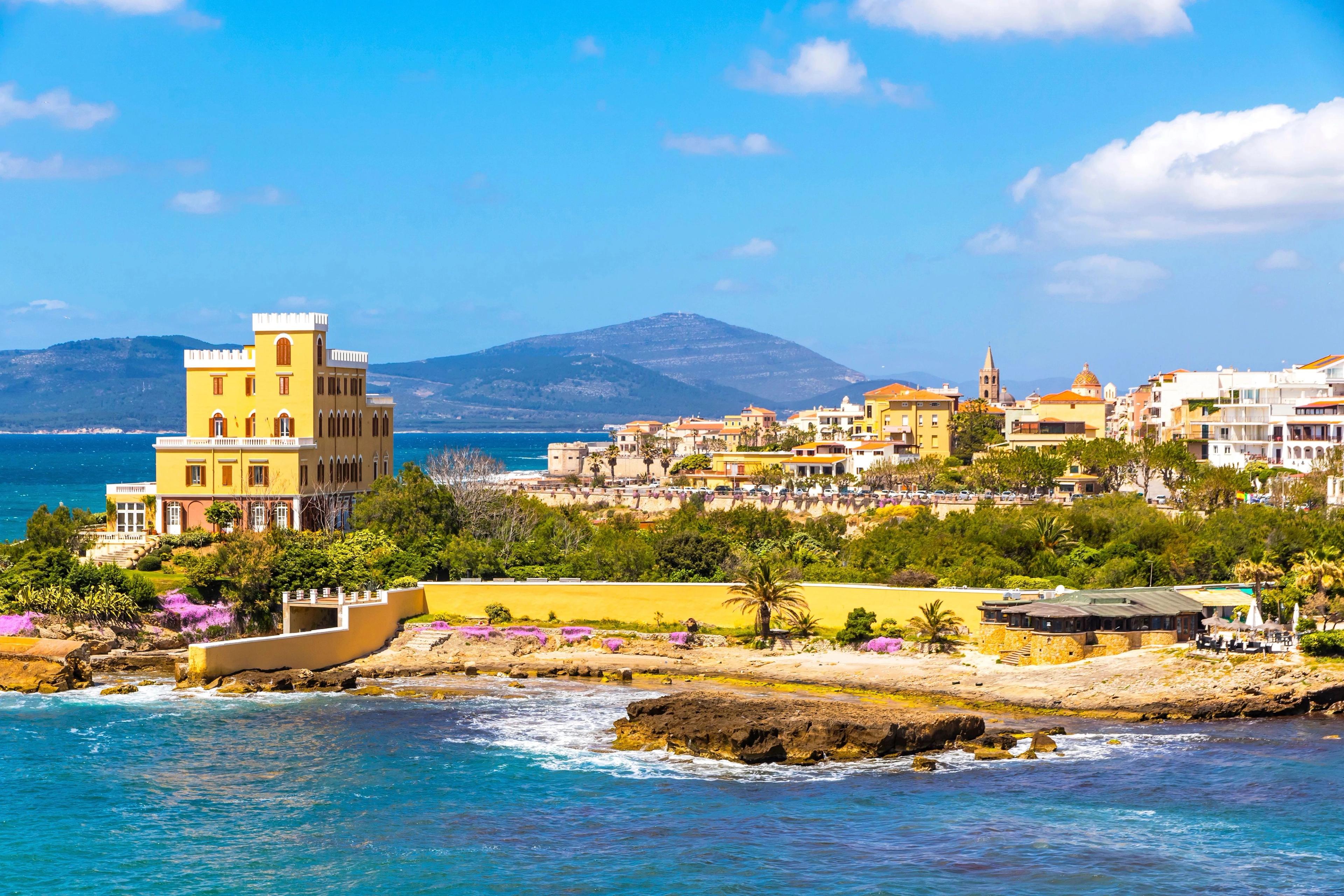 Sardinia rugged rocky coastal cliffs framing translucent turquoise Mediterranean waters under sunny skies. 