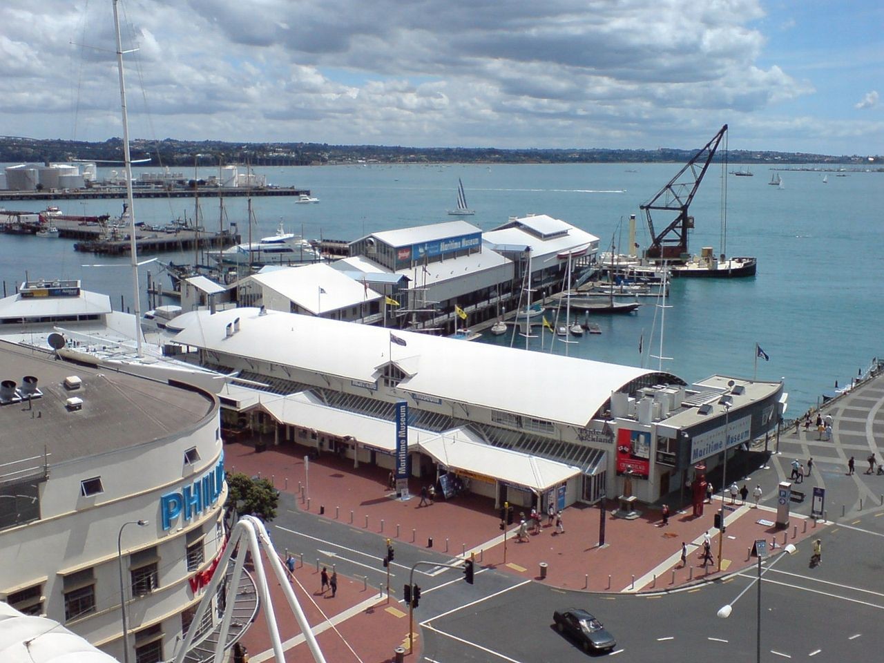 View overlooking the Maritime Museum in downtown Auckland. The museum is within the large sheds on the wharf to the left. The floating crane at the north end is part of the museum and can be explored, including the interior. /Photo from English Wikimedia by View by Ingolfson