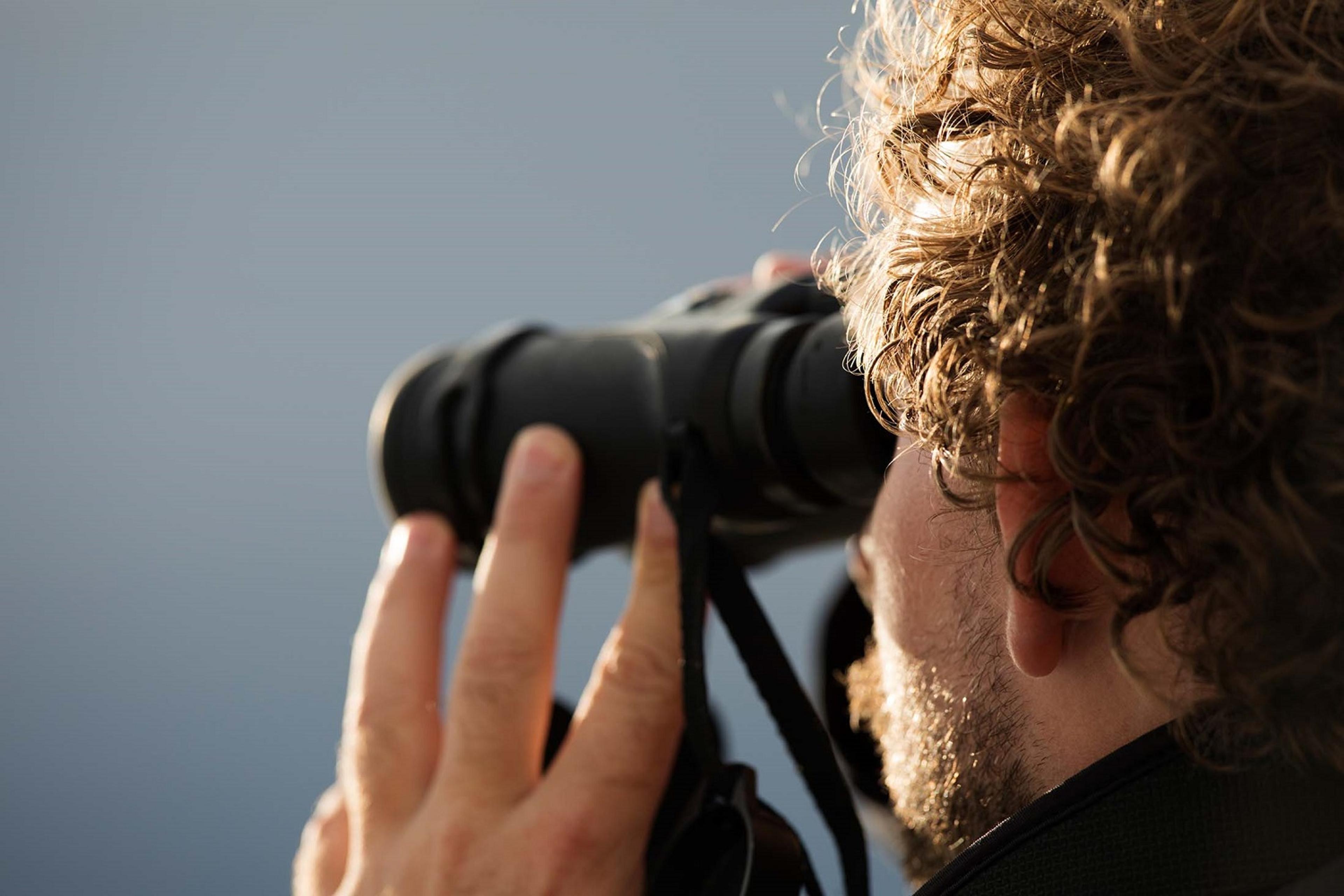 One of Silversea's Expedition Leaders, Brad Siviour, searches for bears using binoculars in Kukak Bay, Alaska./Lucia Griggi