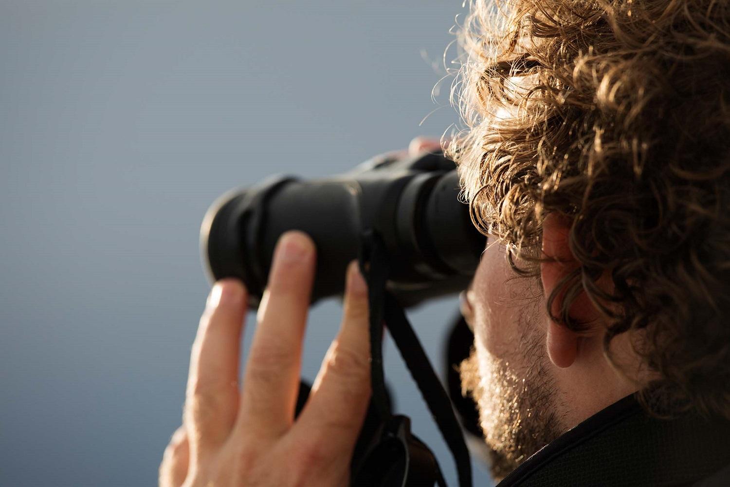 One of Silversea's Expedition Leaders, Brad Siviour, searches for bears using binoculars in Kukak Bay, Alaska./Lucia Griggi